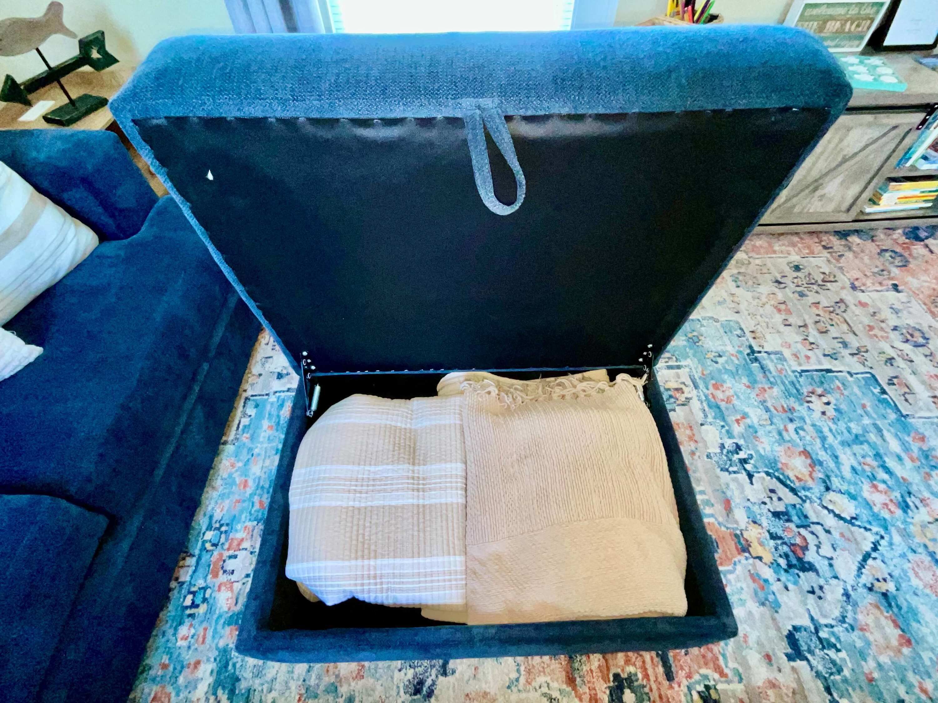 Une pièce avec un canapé bleu, un tapis à motifs et un lit recouvert d’une couverture à rayures.