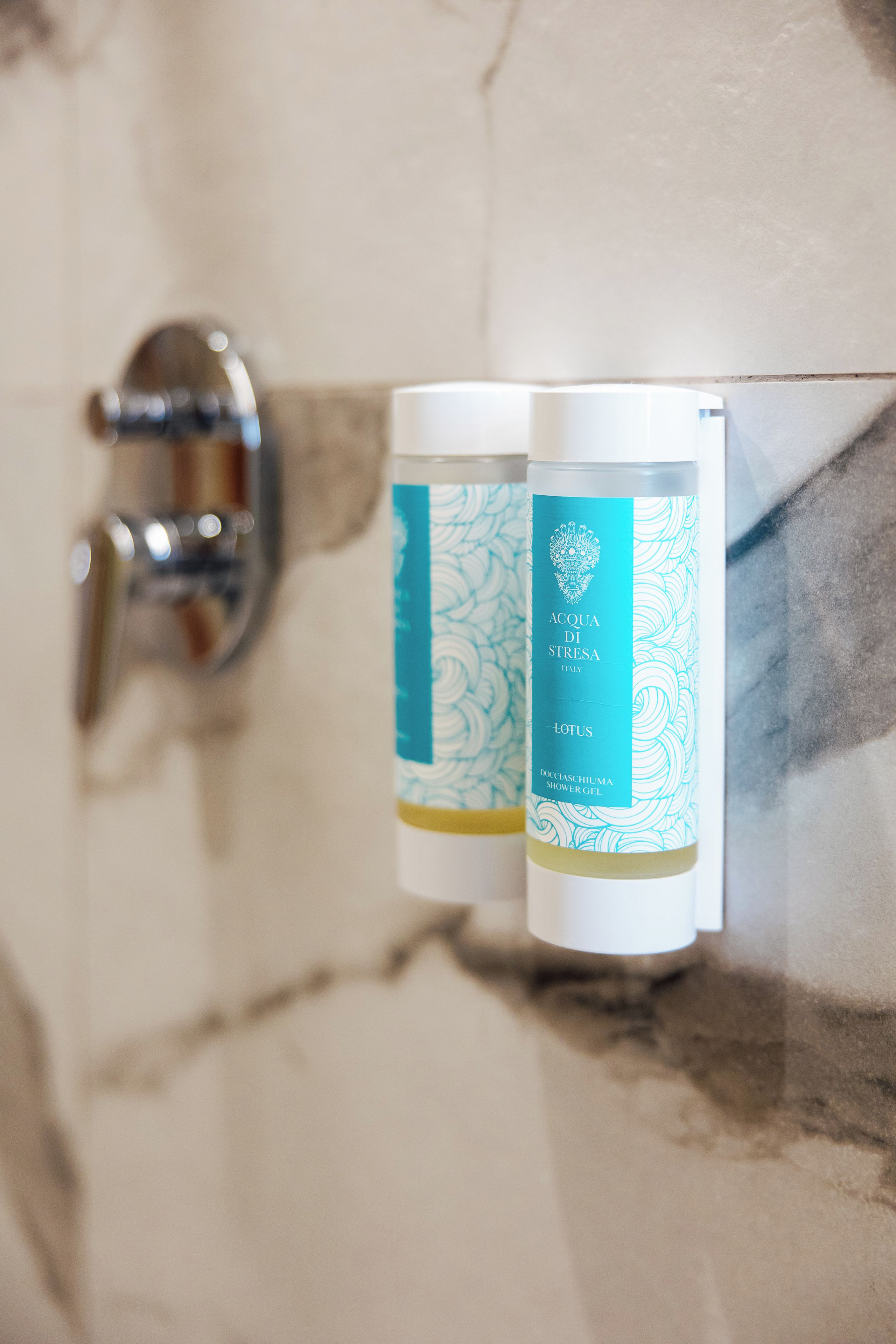 Dos botellas de gel de ducha Acqua di Stresa sobre una pared de mármol.