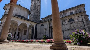A historic building with a clock tower, arches, and a garden with flowers. - Residence Cosy Baveno (Baveno)