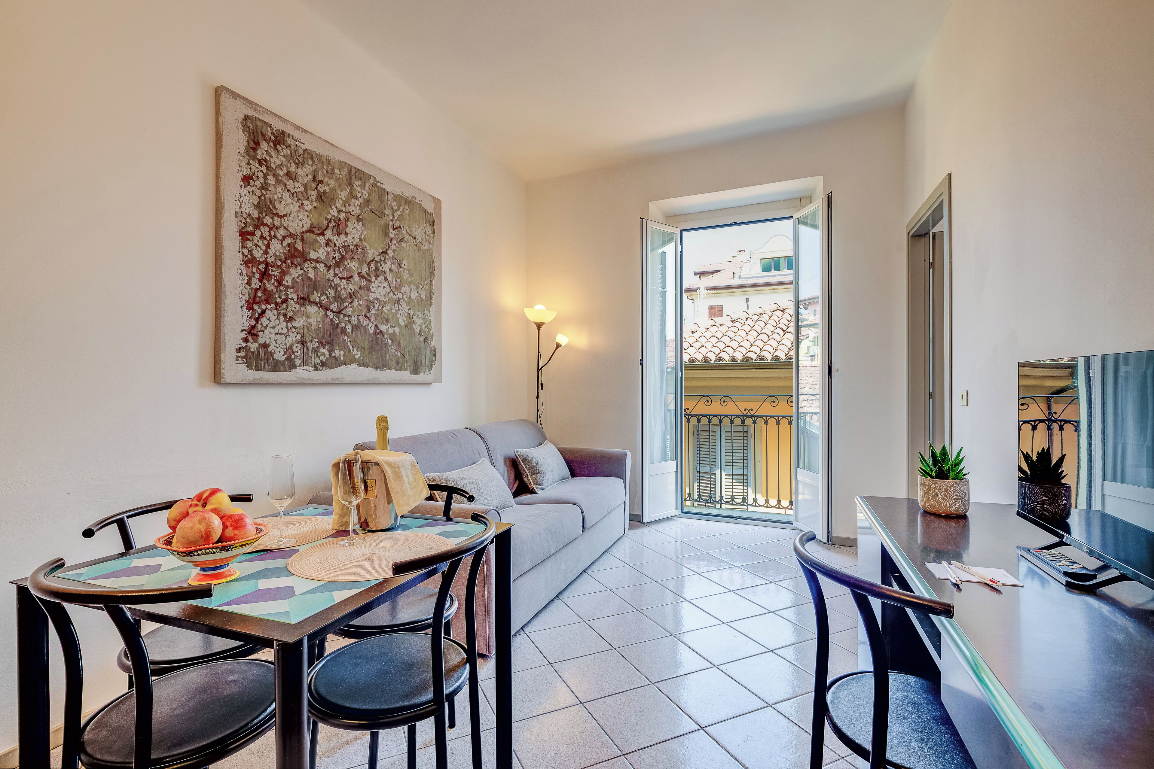 Una sala moderna con comedor, un sofá, una mesa con frutero y un cuadro en la pared.