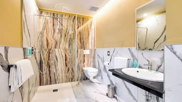 A modern bathroom with a marble shower wall, a toilet, a sink with a black countertop, and a mirror.