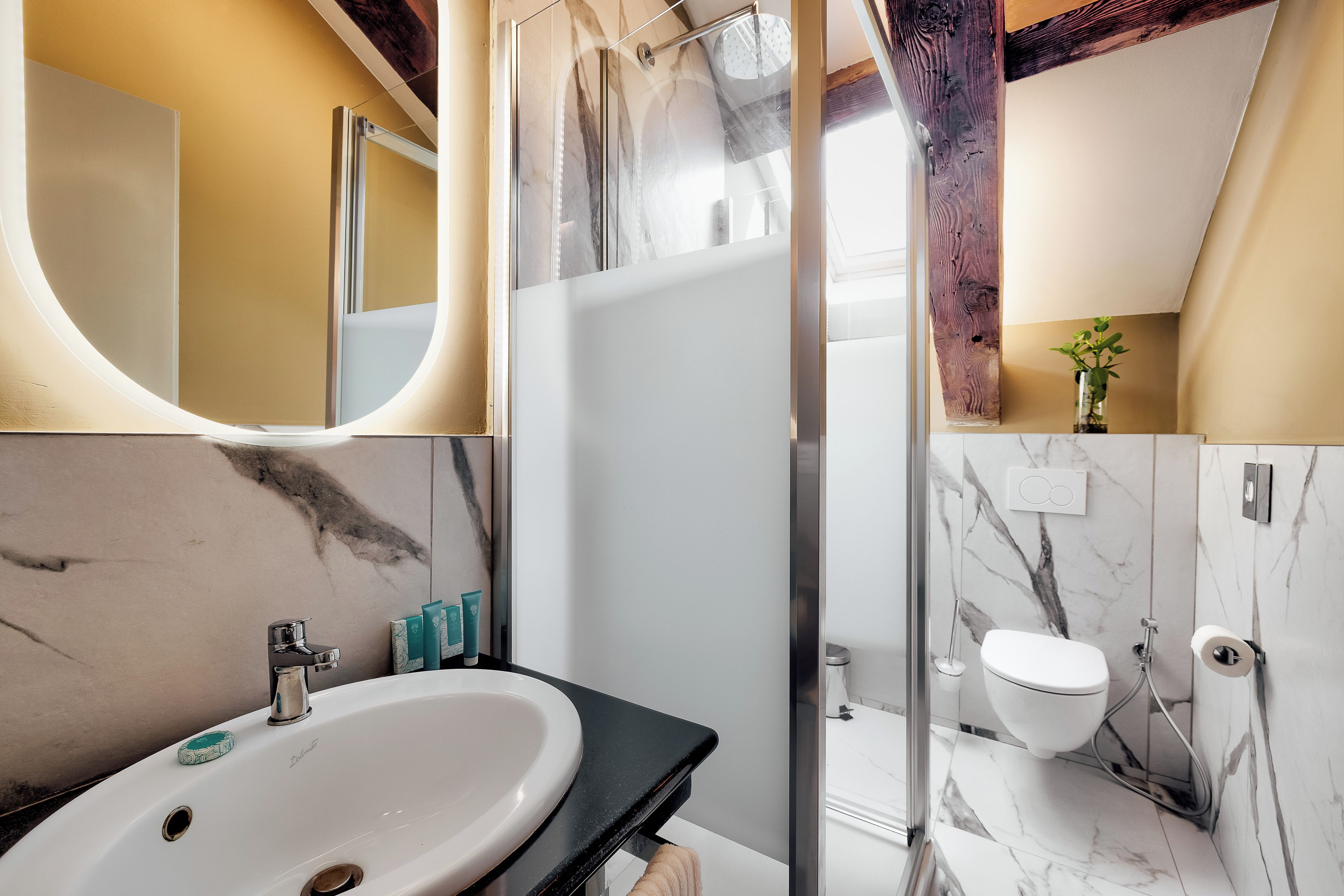 Une salle de bain moderne avec un grand miroir, un lavabo et un espace douche.