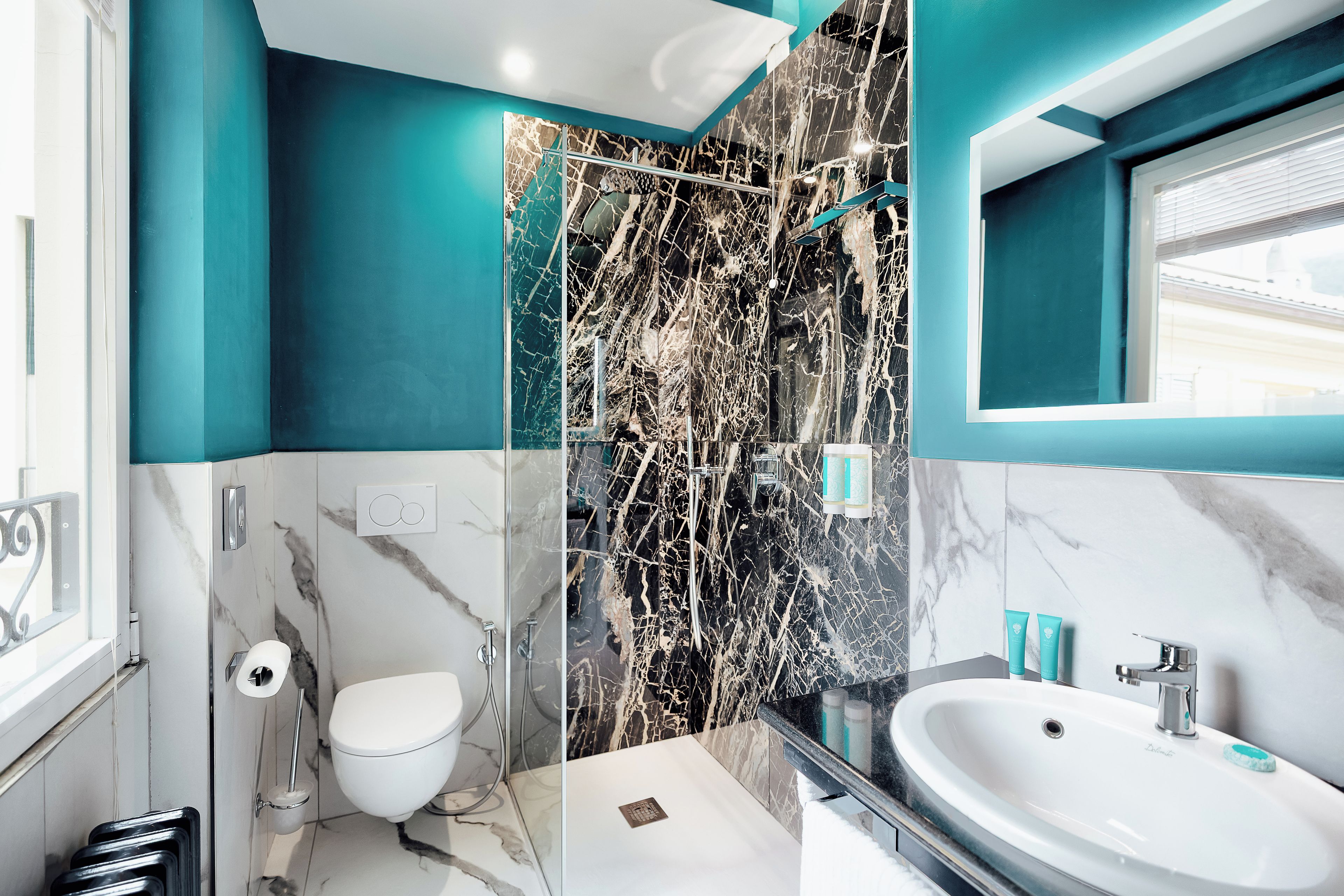 Un bagno moderno con cabina doccia in vetro, un water bianco e un lavabo con piano in marmo.