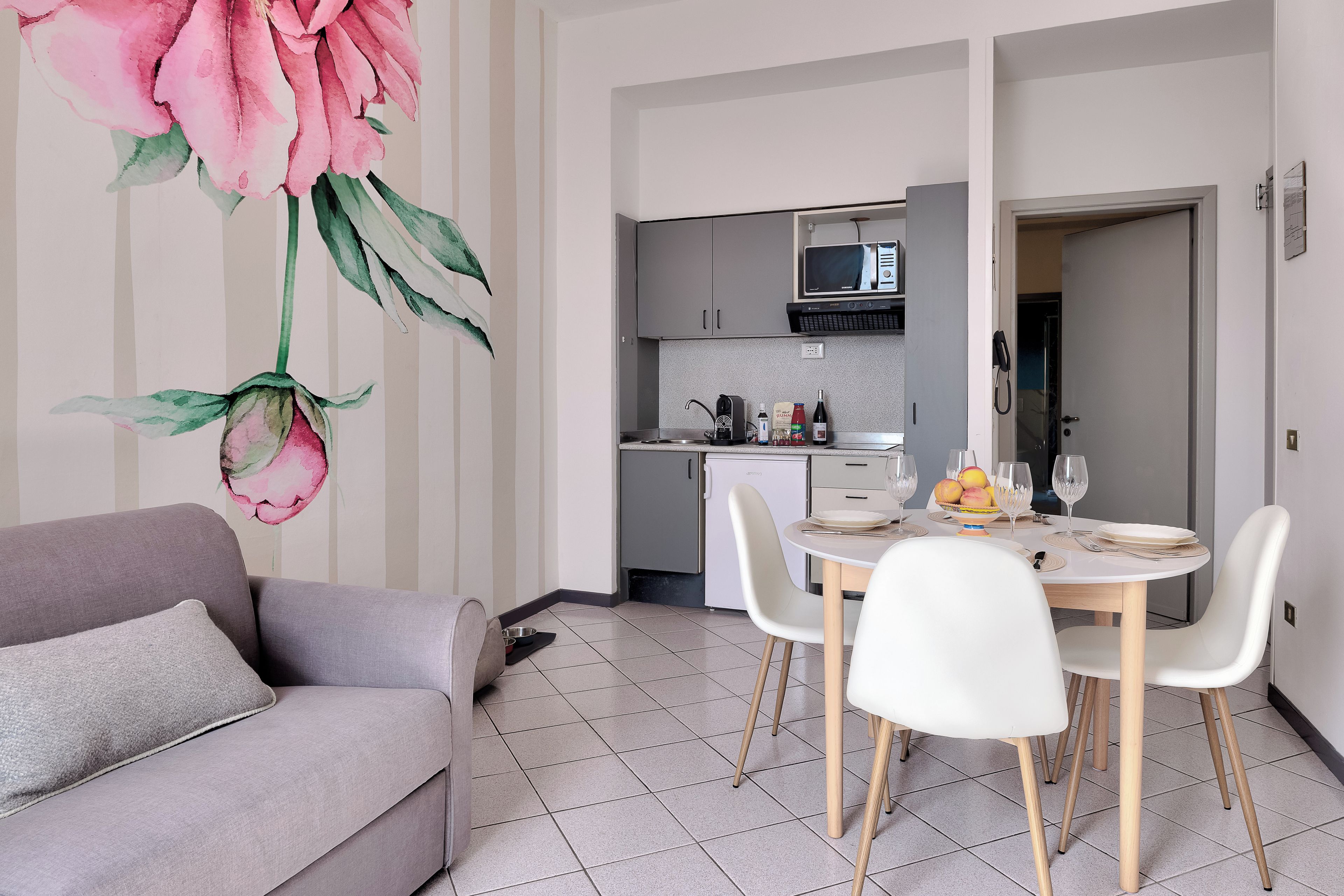 A modern kitchen with a microwave, refrigerator, and dining area with white chairs and a table.