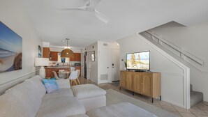 En moderne stue med sofa, fjernsyn og træskab.