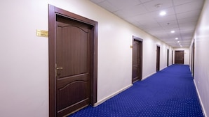 A hotel hallway with wooden doors, a blue carpet, and a ceiling with recessed lighting. - Zad Ajyad (Makkah)