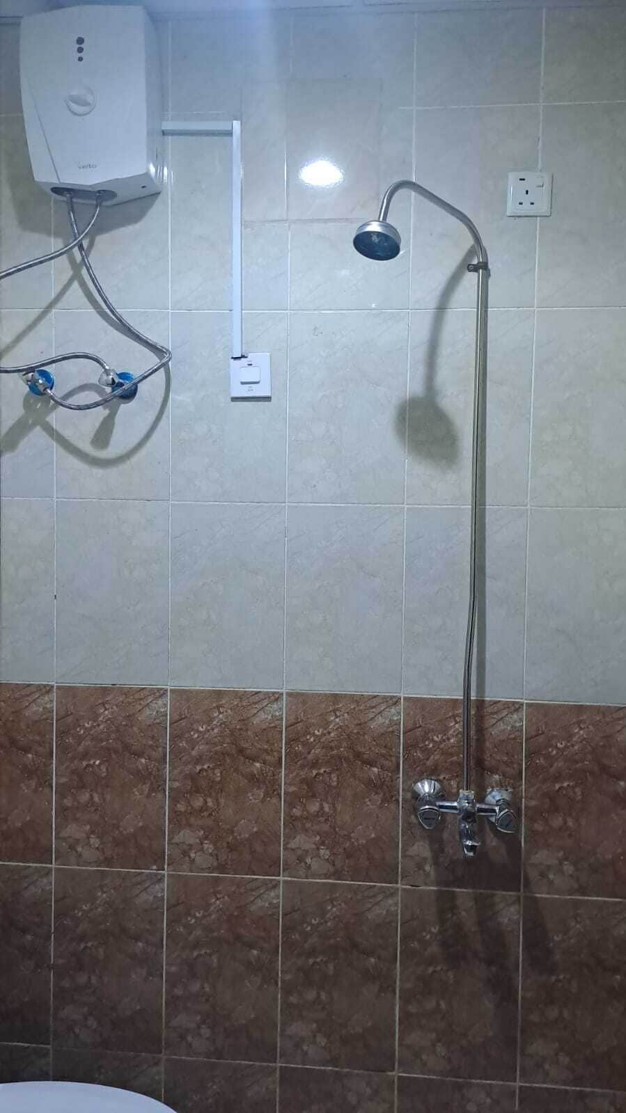 Une salle de bain équipée d’une douche, d’un radiateur mural et d’une prise de courant.