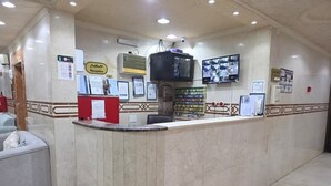 A reception area with a marble counter, a television, and various informational posters. - Zad Ajyad (Makkah)