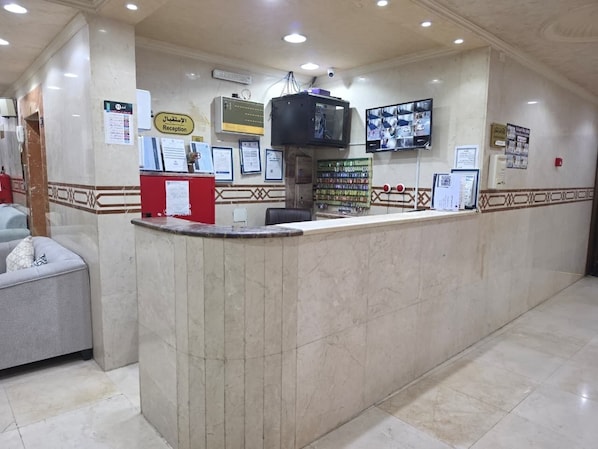 A reception area with a marble counter, a television, and various informational posters. - Zad Ajyad (Makkah)