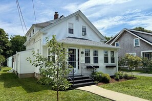 A two-story house with a front porch, a chimney, and a small tree in the yard. - Downtown Hyannis Summer Escape RPAM126 (Hyannis)