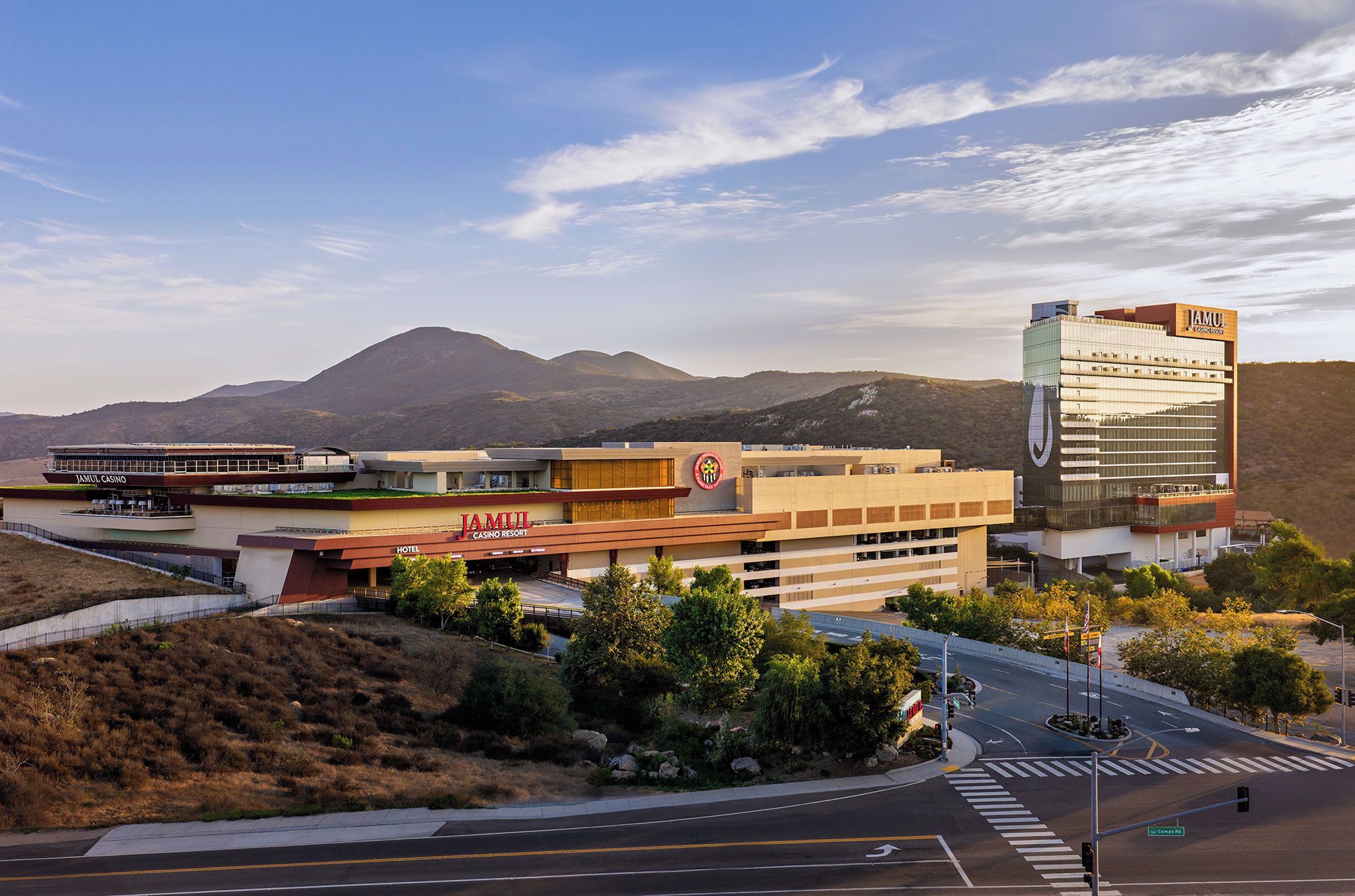 A hotel with a casino, a modern building with a logo, and a mountainous backdrop.