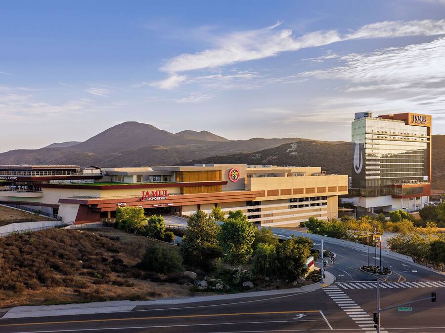 A hotel with a casino, a modern building with a logo, and a mountainous backdrop.
