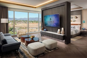 Habitación de hotel moderna con una televisión grande, asientos cómodos, una cama y vistas al paisaje.