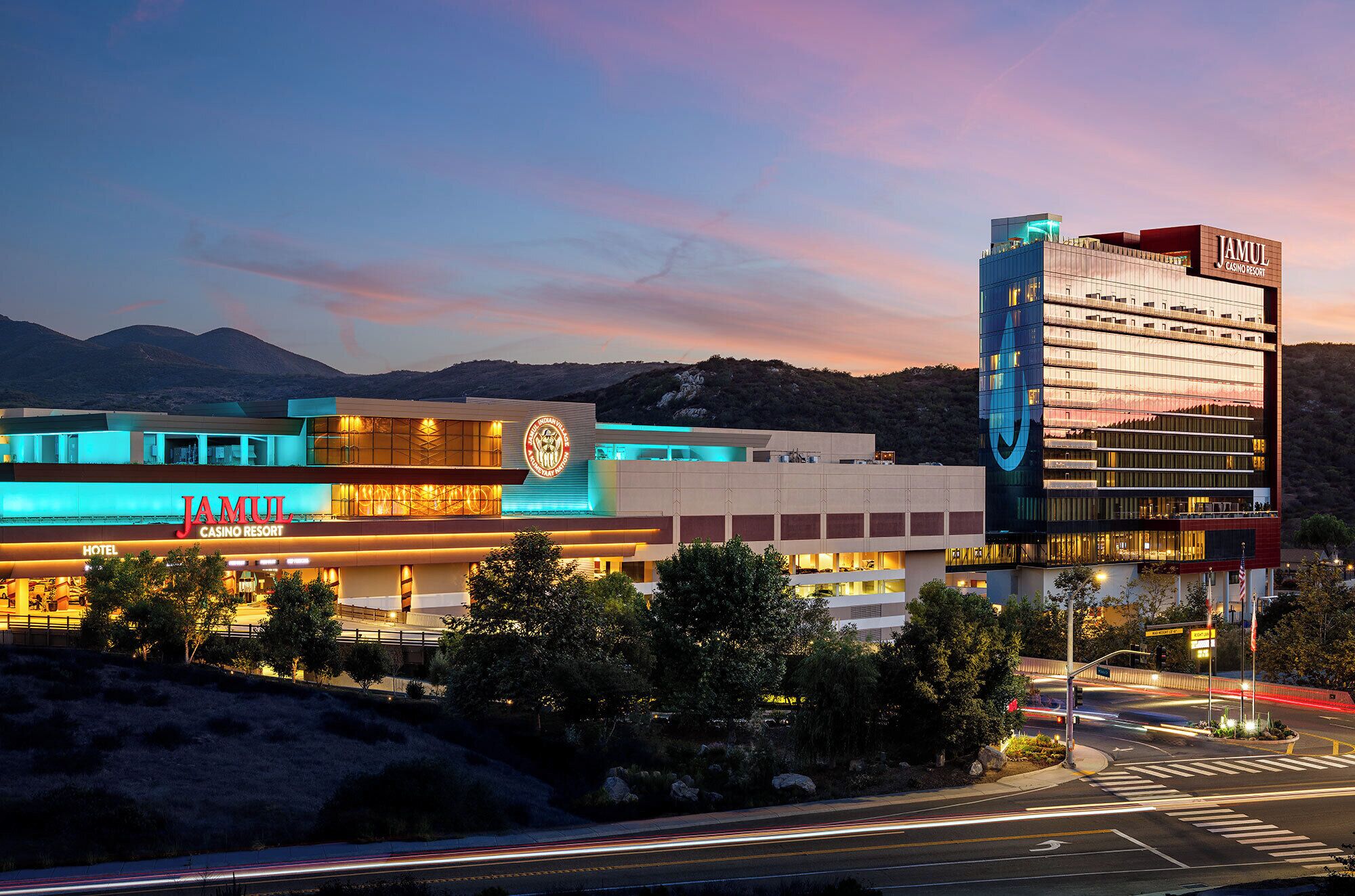A modern hotel with a prominent sign, a large building with a distinctive logo, and a view of the surrounding landscape.