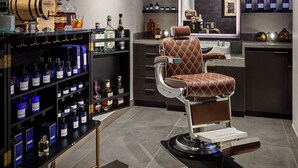 Zona de bar moderna con un espejo grande, un taburete y estantes llenos de botellas.