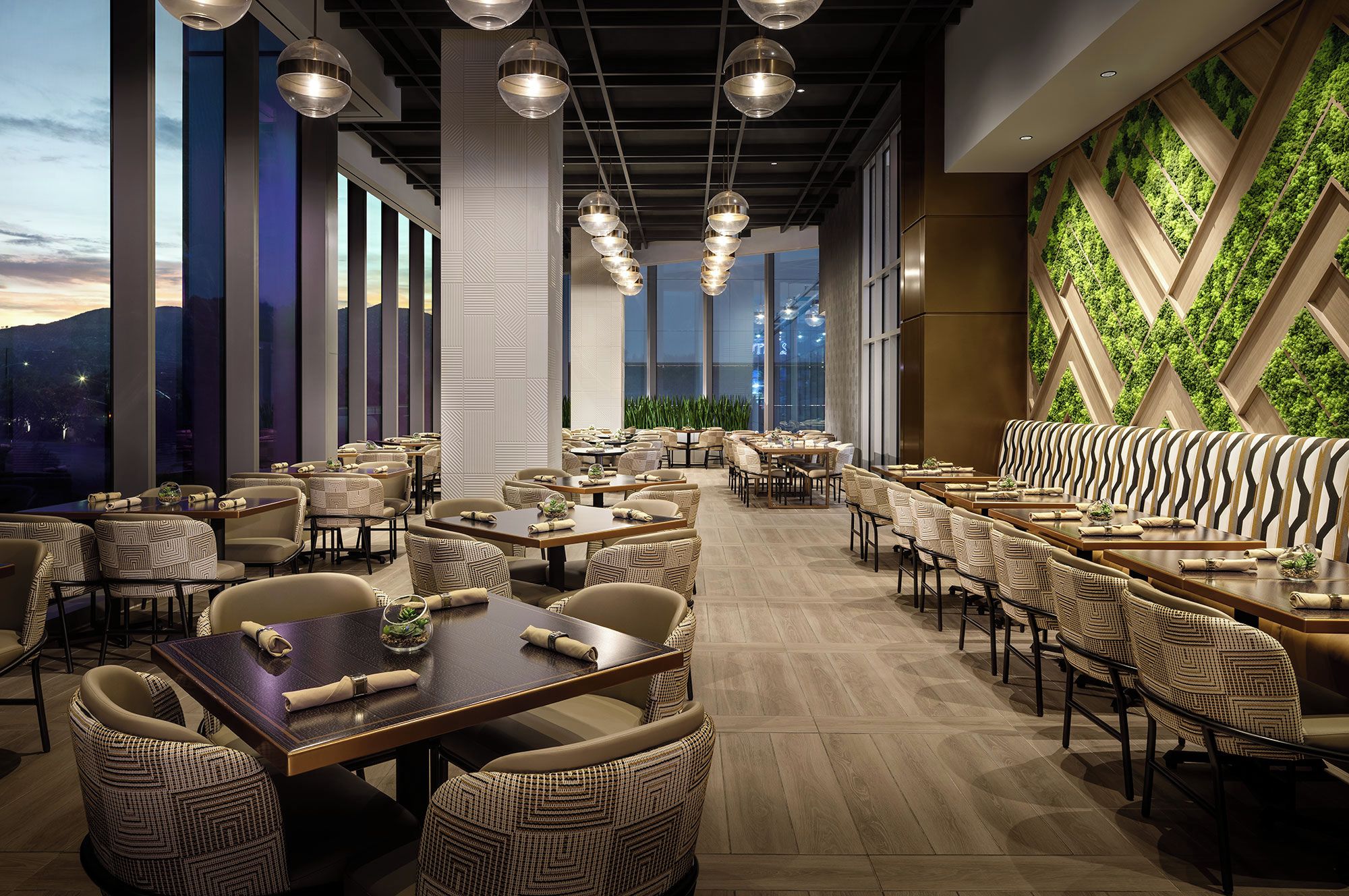 A spacious restaurant with high ceilings, pendant lighting, and a view of the mountains.