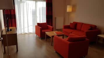 Ein Wohnzimmer mit einer Couch, Sesseln, einem Couchtisch, einer Lampe und einer Heizung.