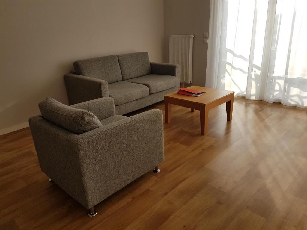 A living room with a sofa, a smaller armchair, and a wooden coffee table.