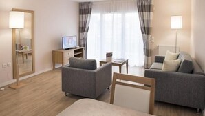 A modern hotel room with a sofa, armchair, TV, and a mirror. - Domitys - Le Carroussel (Cabourg)