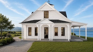 A white, single-story house with a gabled roof, a covered porch, and a view of a lake. - Lakefront Slide House - Bear Lake - New (Fish Haven)
