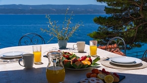 Ein Tisch mit Frühstücksangeboten, einem Saftkrug und Meerblick.