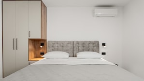 Ein Schlafzimmer mit einem Bett, einem Kleiderschrank, einem Regal und einer Klimaanlage.