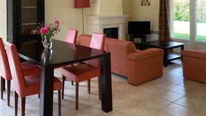A spacious living area with a dining table, chairs, sofas, a fireplace, and a television.