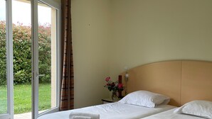 A double bed with white linens and a nightstand with a vase of flowers.