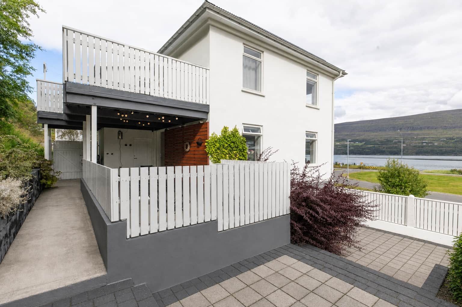 A modern two-story house with a balcony, a garage, and a view of a lake.
