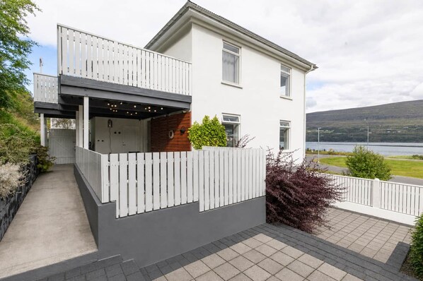 A modern two-story house with a balcony, a garage, and a view of a lake.