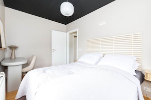 Une chambre à coucher avec un lit, une table de chevet, une chaise, une lampe de chevet et une porte.