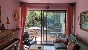 A living room with a piano, a sofa, a table, and a view of the garden through a sliding door. - Small house with a garden in the heart of Old Antibes (Antibes)