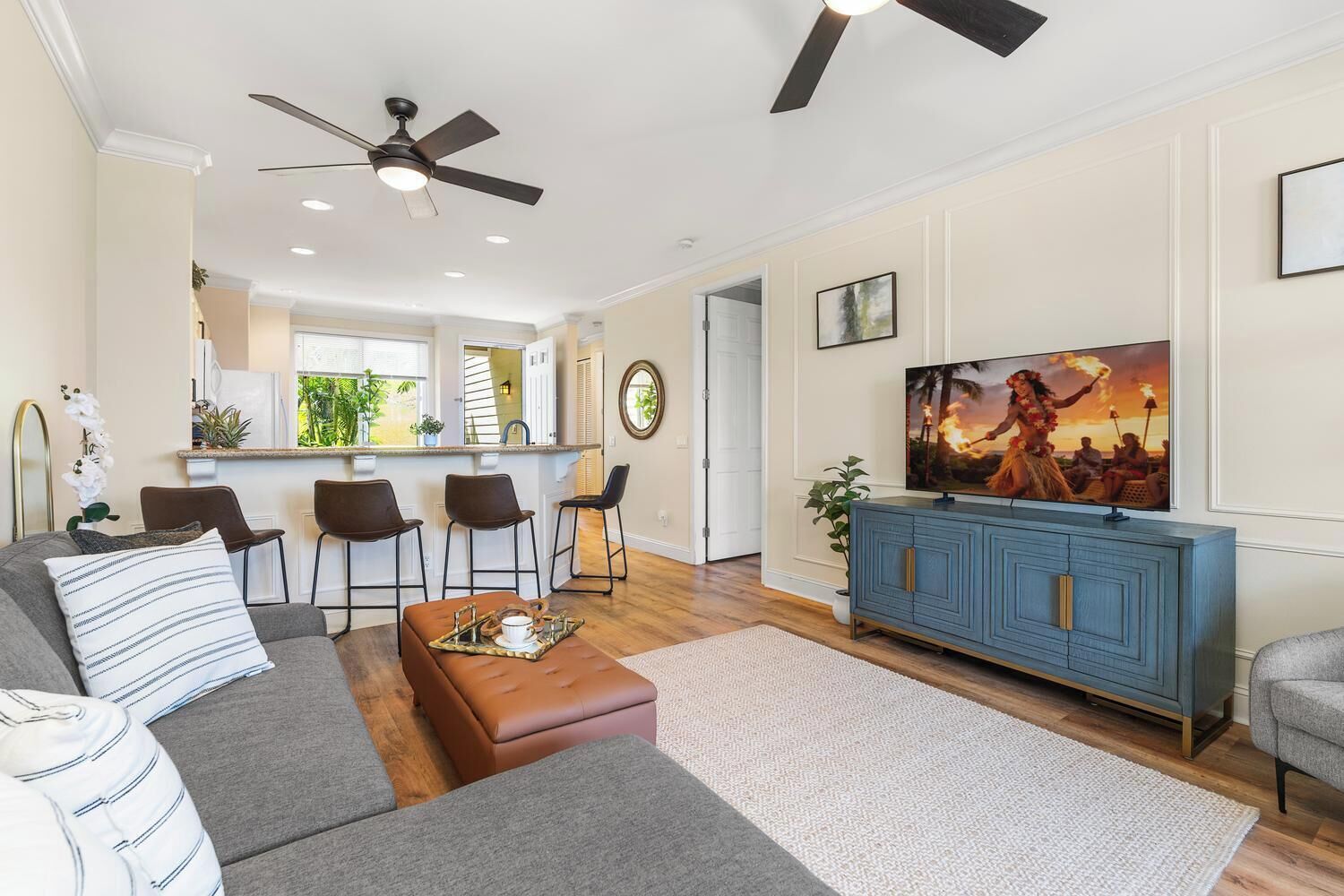 A modern living room with a sofa, ottoman, and a TV on a blue cabinet.