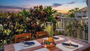 Een houten tafel gedekt voor twee personen, met een ananas als middelpunt, omringd door weelderige tropische planten.