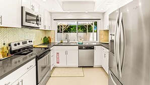 Una cocina moderna con electrodomésticos de acero inoxidable, muebles de color blanco y un backsplash de baldosas en patrón de espiga.