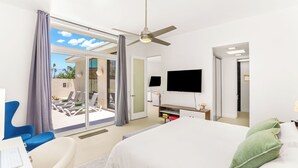 Una habitación de hotel con cama, escritorio, silla, televisor y balcón con sillas.