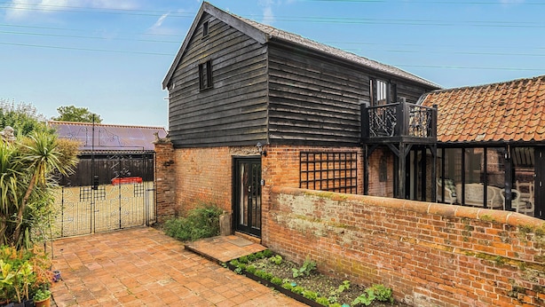 A traditional building with a brick exterior, a tiled roof, and a small garden area.