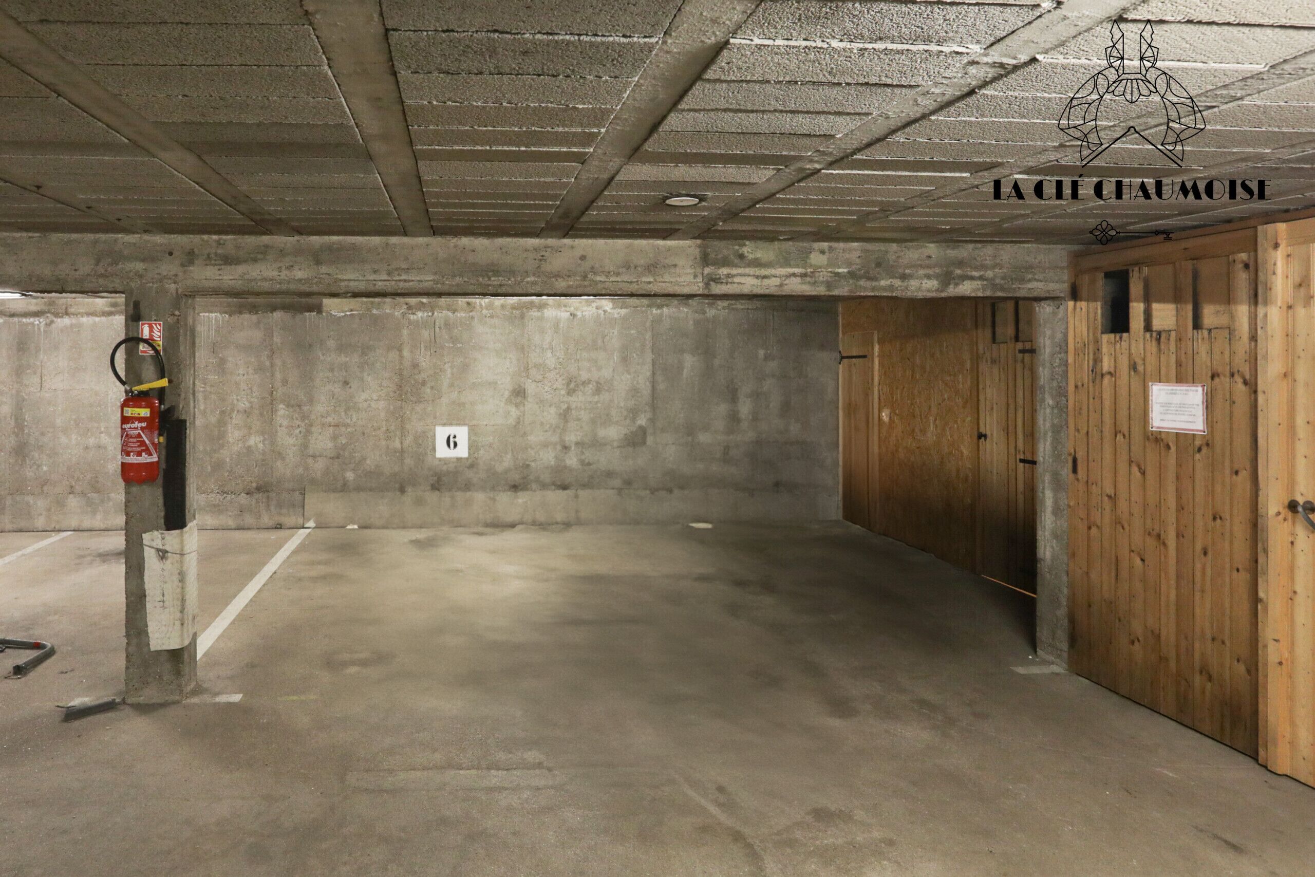A parking garage with concrete walls, a fire extinguisher, and wooden doors.