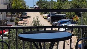 Een balkon met uitzicht op een parkeerplaats en bergen.