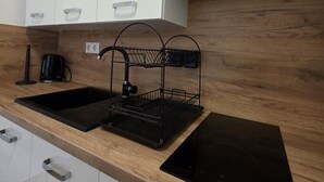Een moderne keuken met witte kasten, een zwart spoelbak en een koffiezetapparaat, plus een zwart inductiefornuis.