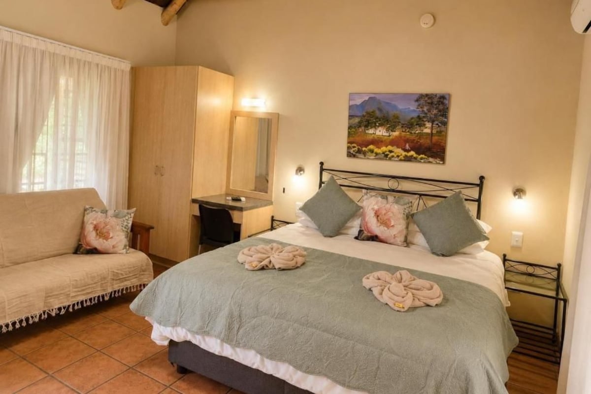Ein Schlafzimmer mit Bett, Sofa, Schreibtisch und einem Gemälde an der Wand.