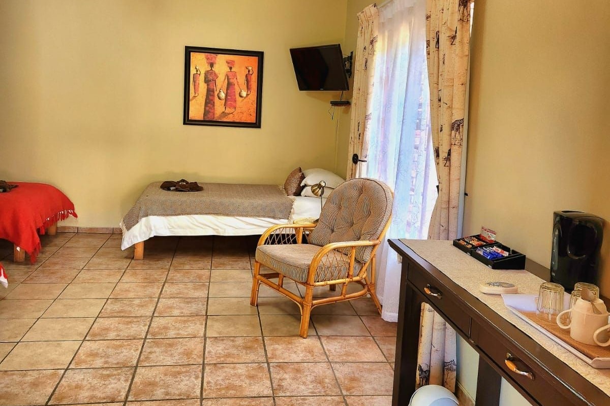 Ein Zimmer mit einem Bett, einem Sessel, einem Schreibtisch, einem Fernseher und einem Bild an der Wand.