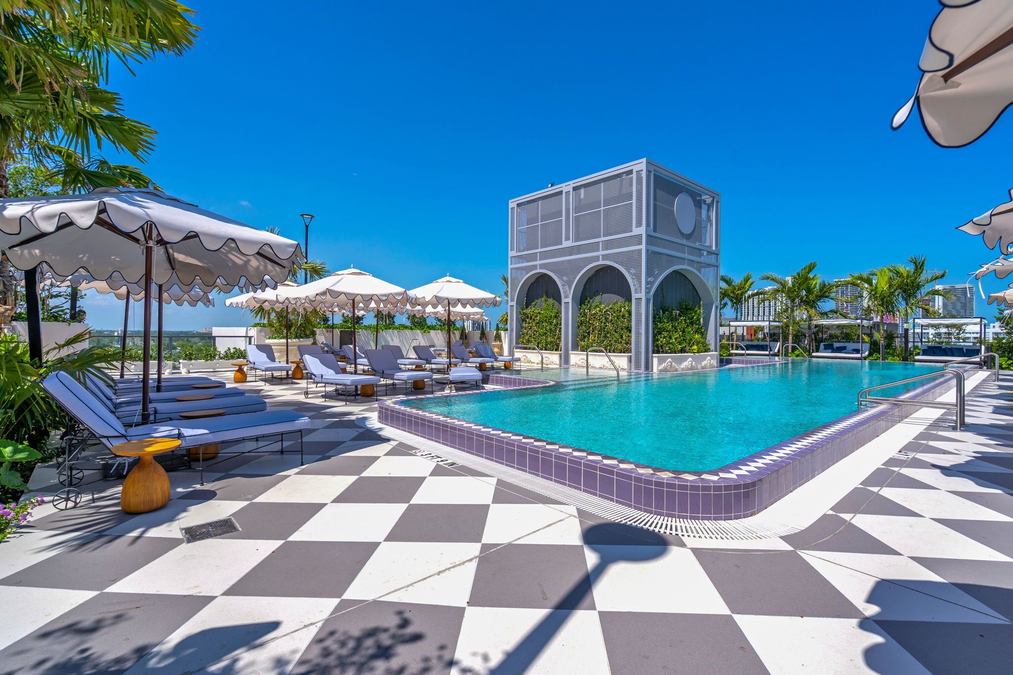 A pool area with lounge chairs, umbrellas, and a distinctive building structure.