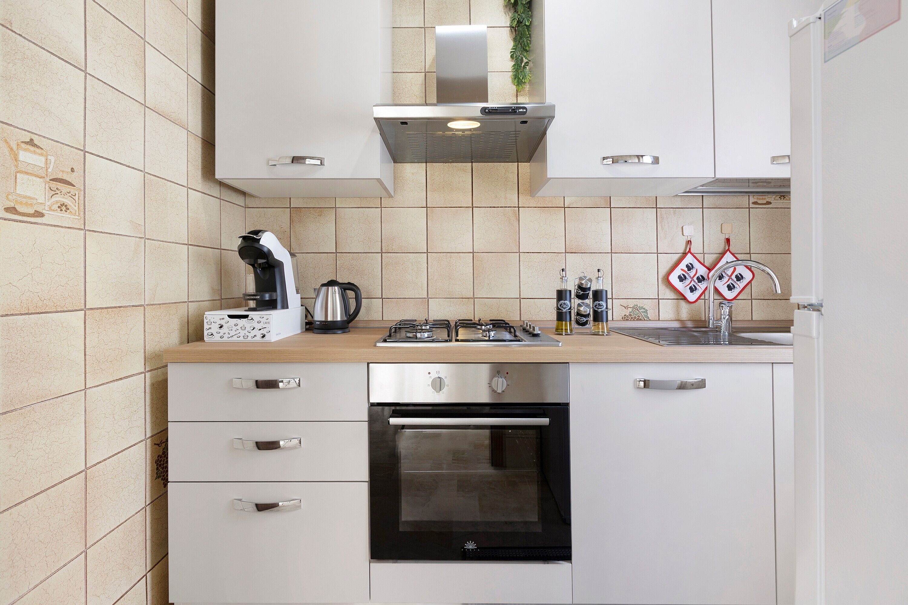 A modern kitchen with a gas stove, oven, and a coffee maker.