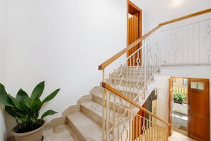 Eine Treppe mit hölzernen Geländern, einem Blumentopf und einer Tür zu einem anderen Raum.