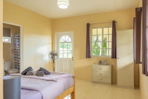 A room with a bed, a fan, a window with curtains, a wardrobe, and a small table with pictures. - Pierocks Highgate with  Free Parking , WI-FI (Arnos Vale)