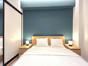 Ein Hotelzimmer mit einem Bett, zwei Nachttischen und einem Schreibtischchen mit einer Lampe.