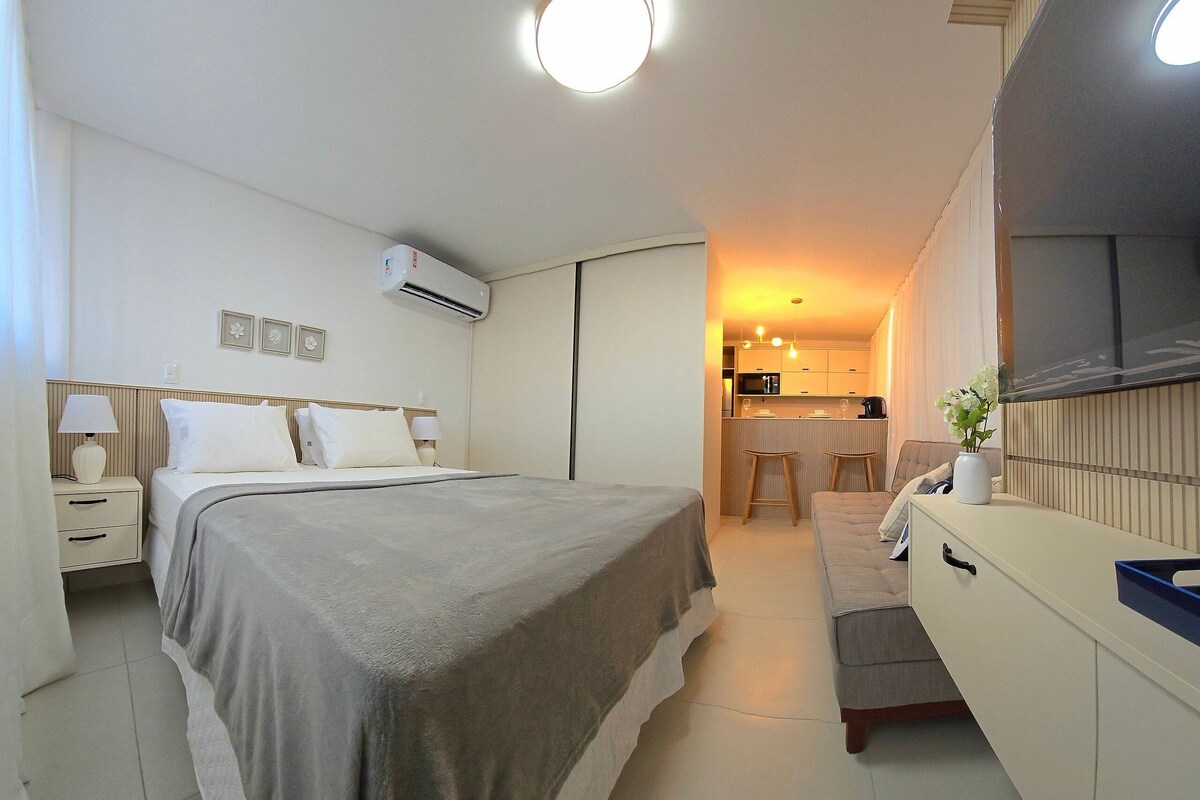 Ein Schlafzimmer mit Bett, Nachttischen, Klimaanlage, Schreibtisch und Stuhl.