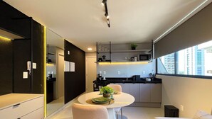 A modern kitchen with a dining area, a sofa, and a view of the city. - Voll29 by Hosppedar (João Pessoa)