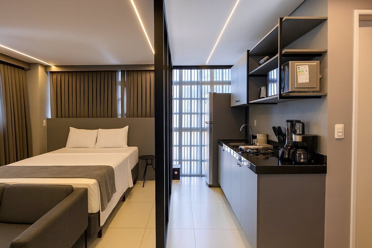 Ein Hotelzimmer mit Bett, Schreibtisch und einer Küchenzeile.